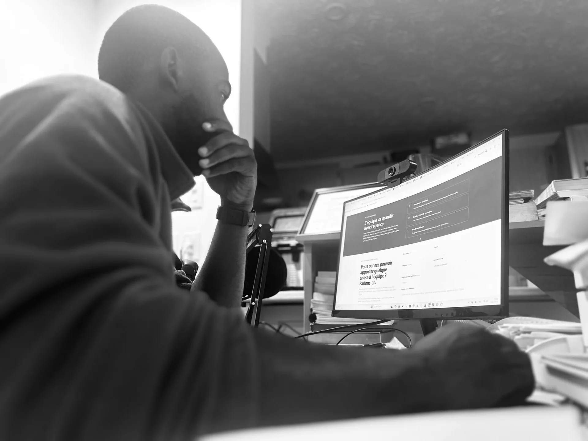 Personne devant son écran, en pleine réflexion au travail — photographie en noir et blanc